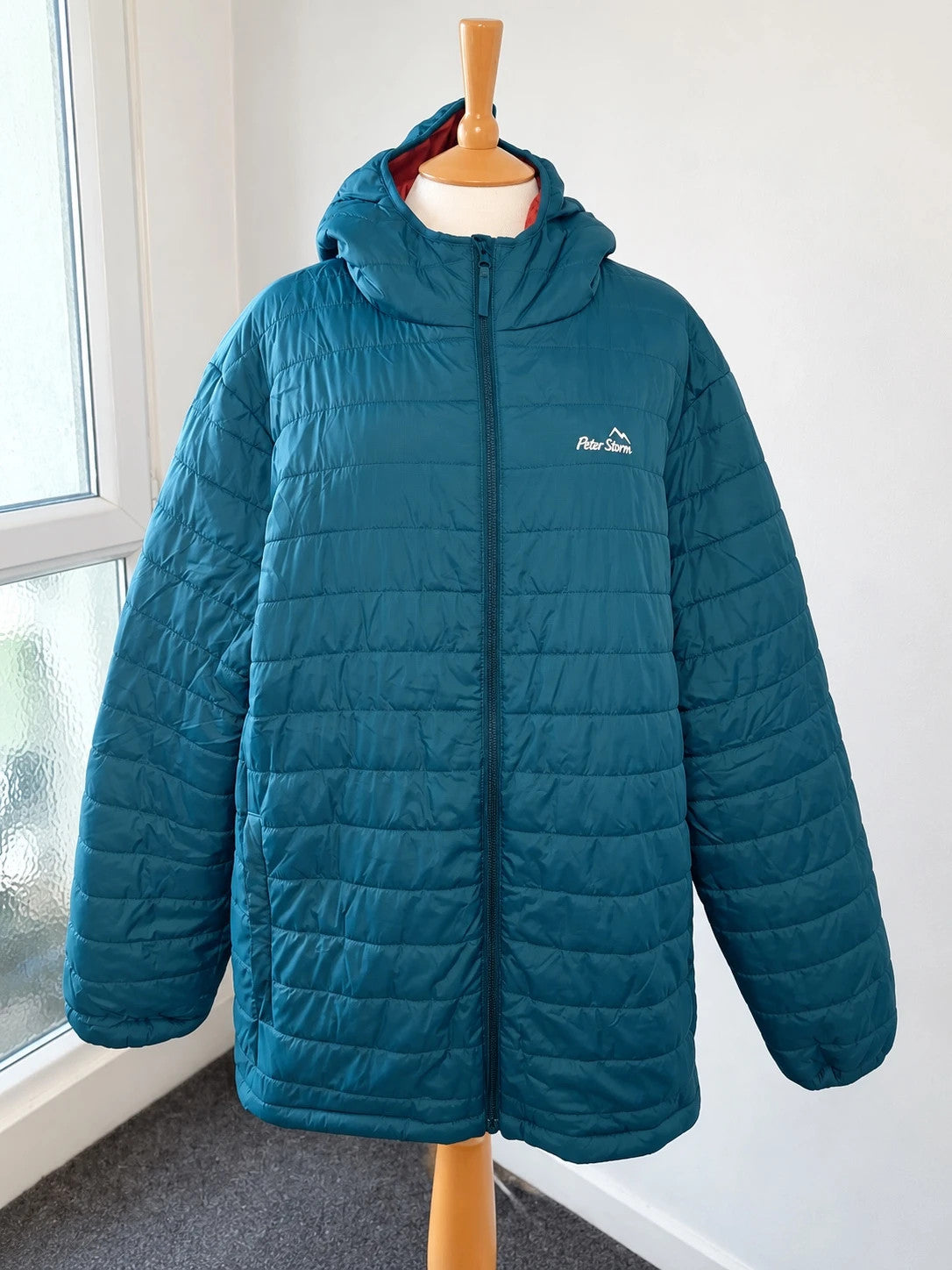 Peter Storm teal blue puffer jacket with hood and contrasting orange lining.
