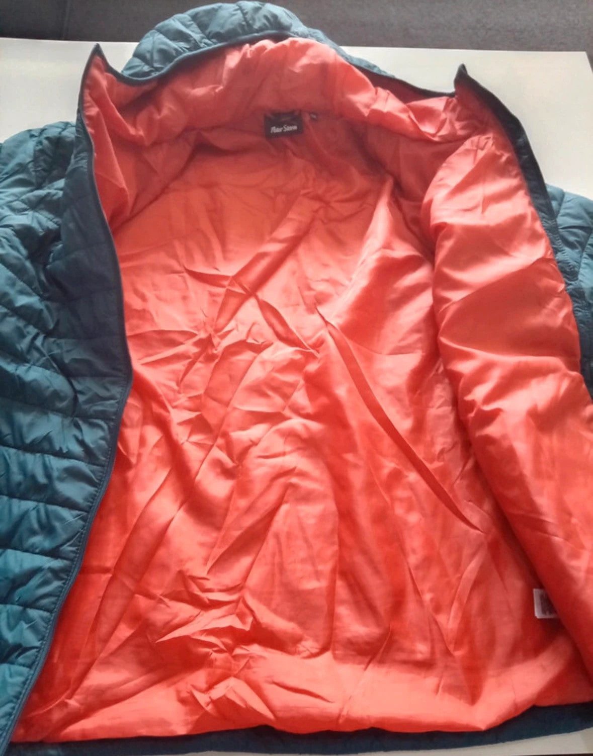 Peter Storm teal blue puffer jacket with hood and contrasting orange lining.