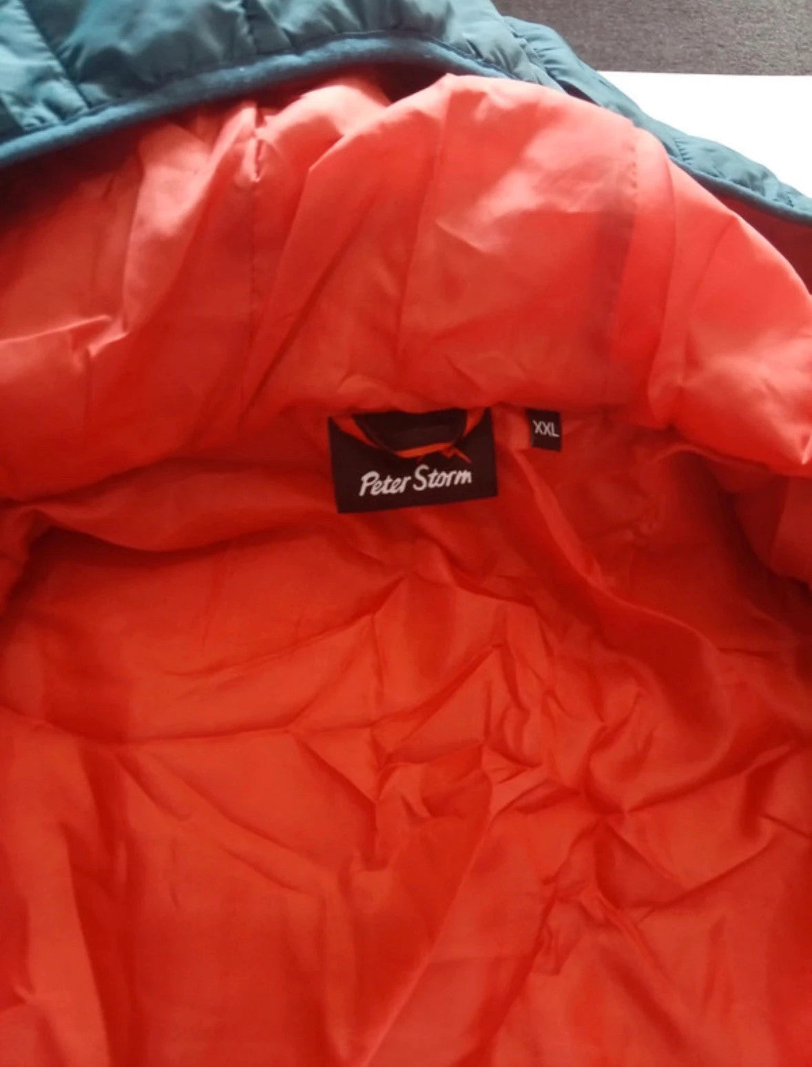 Peter Storm teal blue puffer jacket with hood and contrasting orange lining.